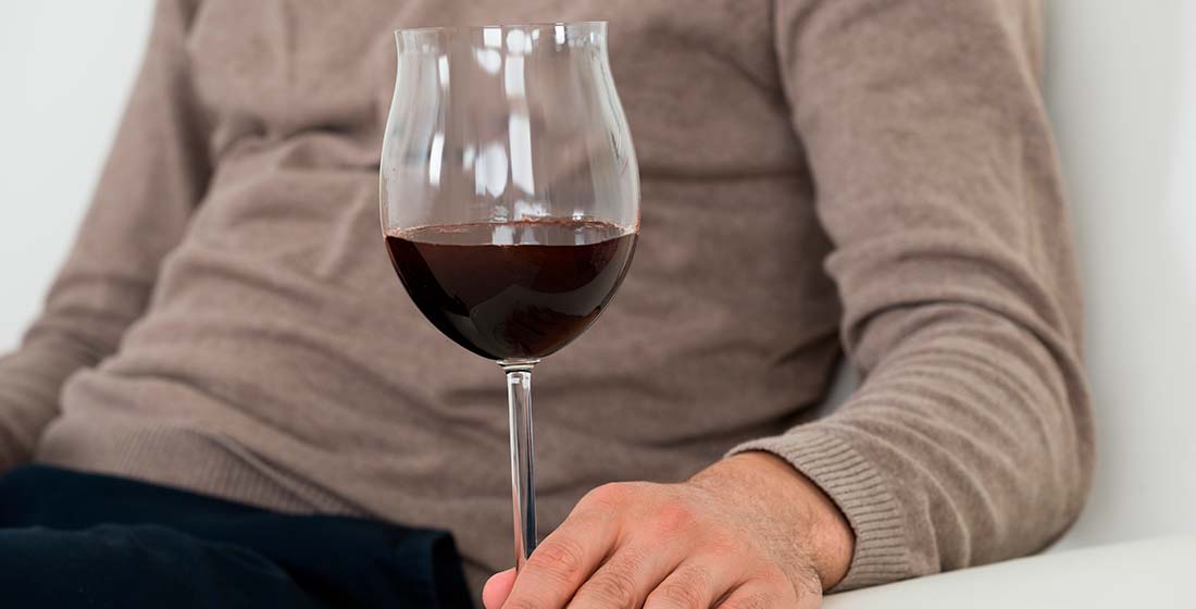 мужчина сидит на диване с бокалом вина в руке