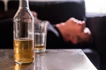 Бутылка и стакан с алкоголем на столе